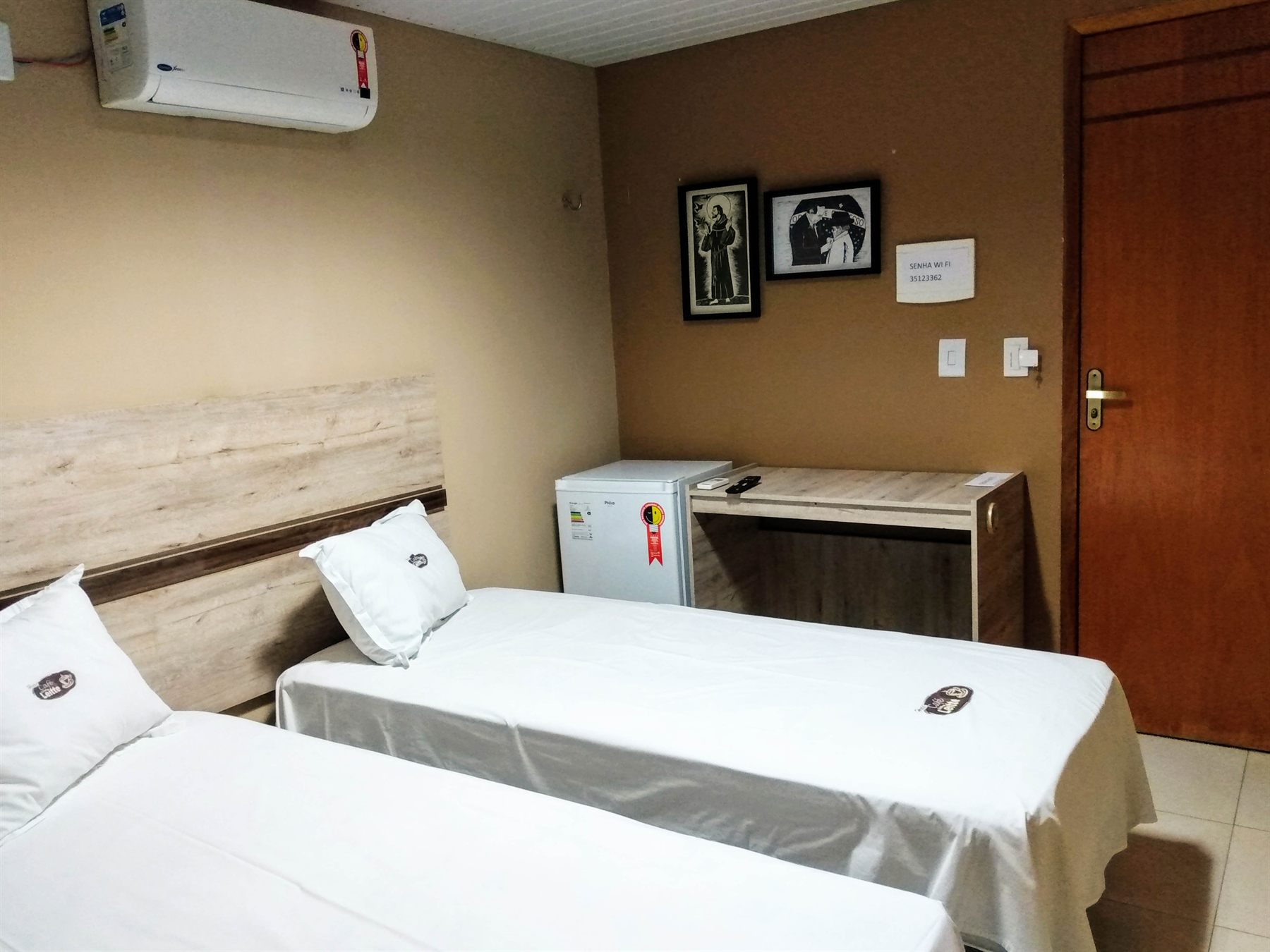 Apartamento da pousada com cama arrumada, ar-condicionado e televisão