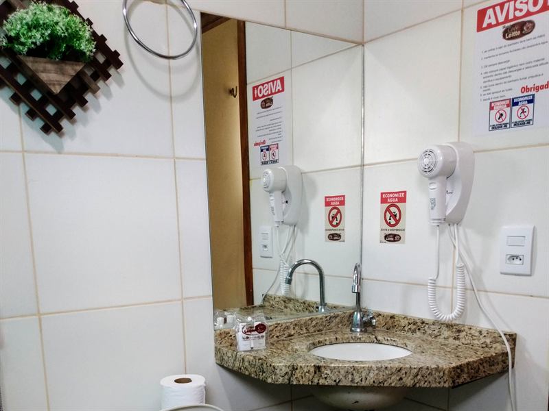 Banheiro do apartamento com bancada de granito, espelho, toalheiro e secador de cabelo fixado na parede