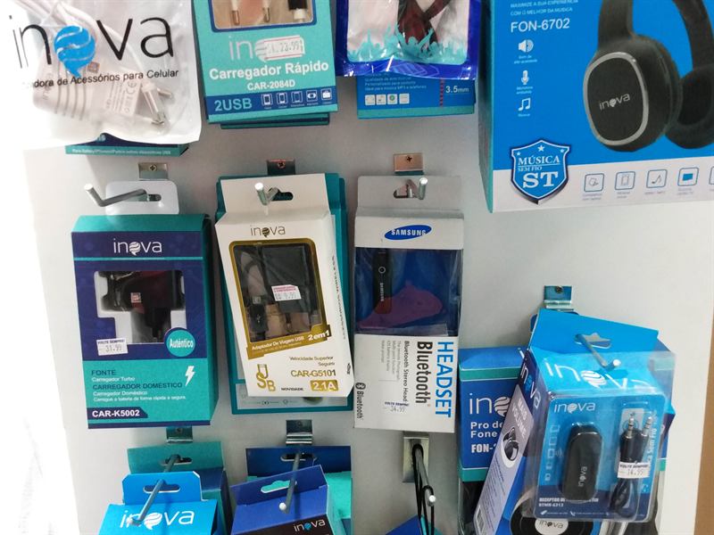 Painel com carregadores, cabos e fones de ouvido embalados, à venda na lojinha da pousada