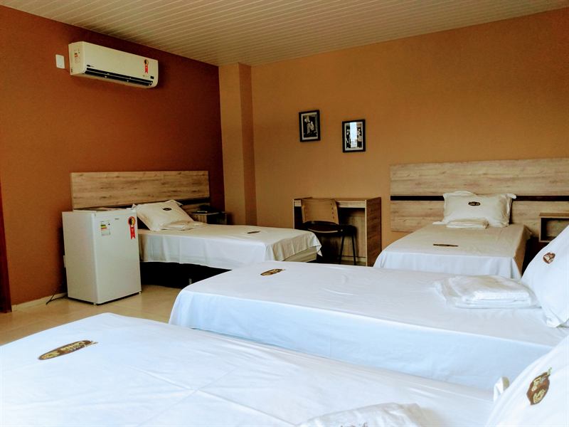 Apartamento amplo com várias camas de solteiro, ar-condicionado, frigobar e escrivaninha de madeira clara