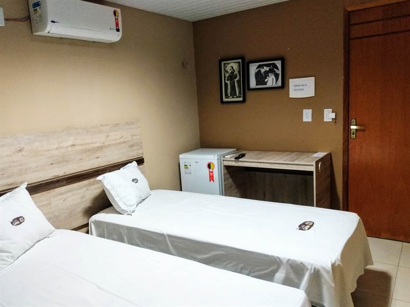Apartamento duplo com duas camas de solteiro, ar-condicionado, frigobar, escrivaninha e aviso do wi-fi na parede