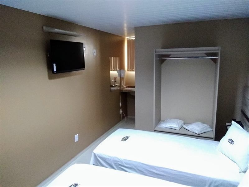 Apartamento com TV de tela plana, armário embutido com travesseiros e bancada com interfone