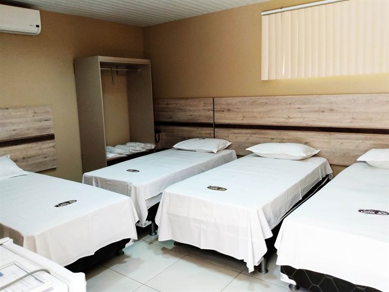 Apartamento para grupos com quatro camas de solteiro, cabeceiras de madeira clara, ar-condicionado e armário